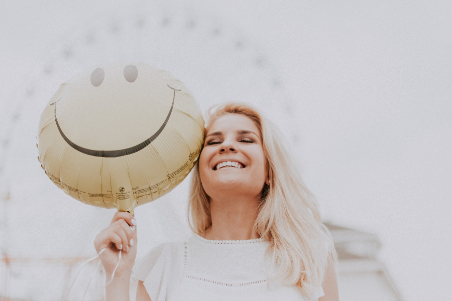 Woman holding balloon while feeling positive, being wary of Toxic Positivity and Addiction Recovery